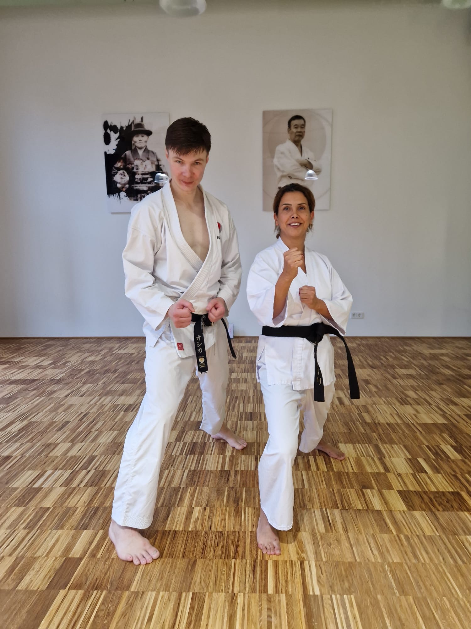 Zwei Karateka in Kamae vor den Porträts der JKA-Meister