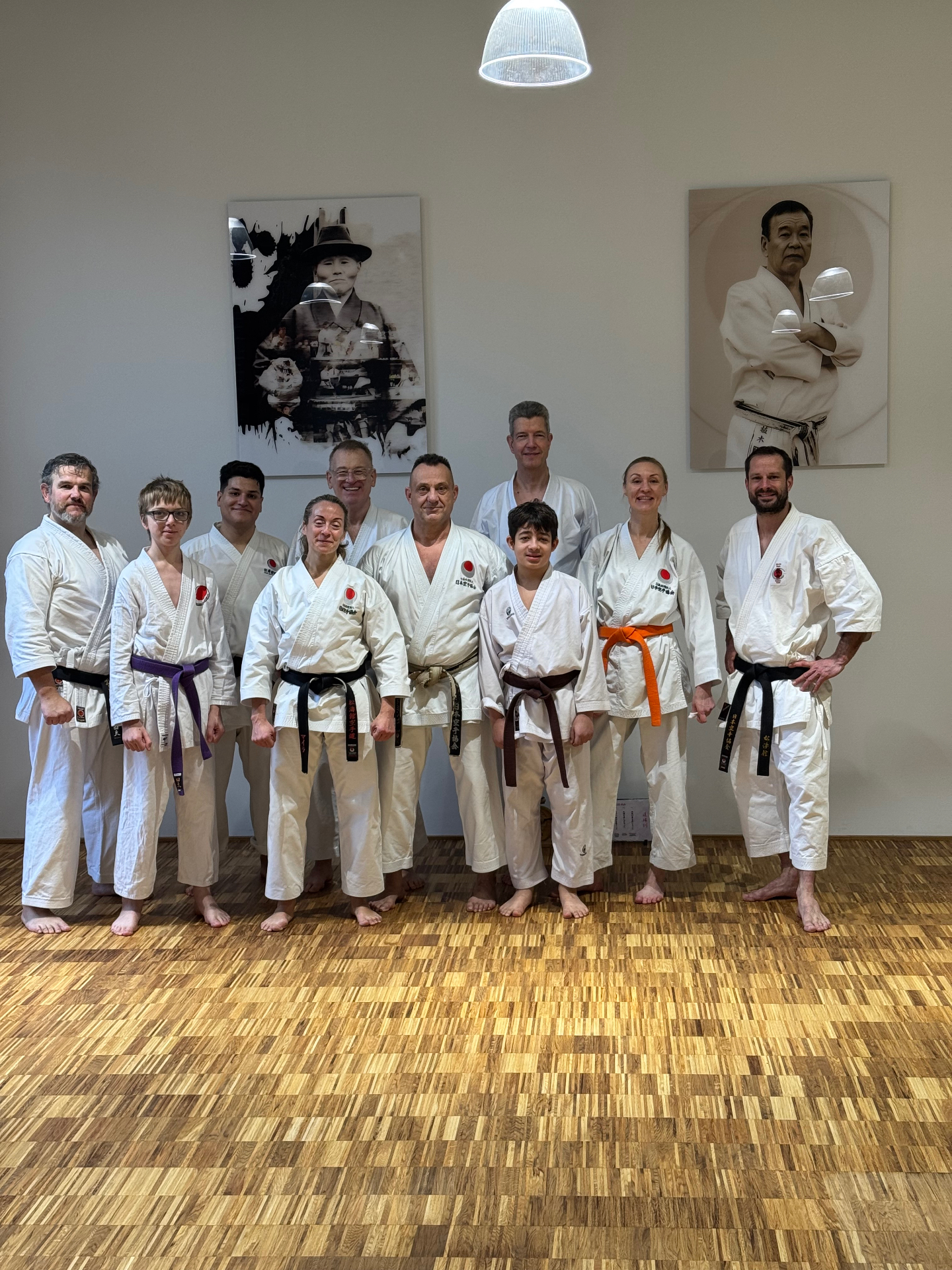 Gruppenfoto im Dojo mit Porträts von Funakoshi Sensei und Ueki Sensei