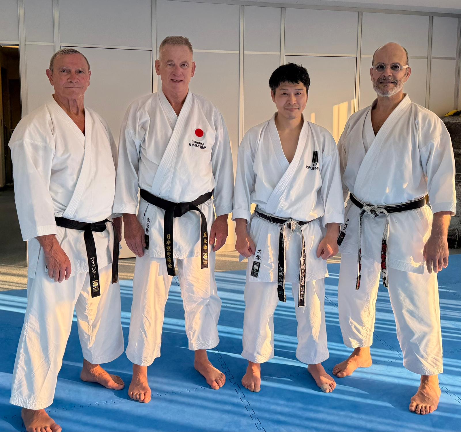 Gruppenfoto im Dojo mit drei Karateka und einem japanischen Sensei nach dem Training