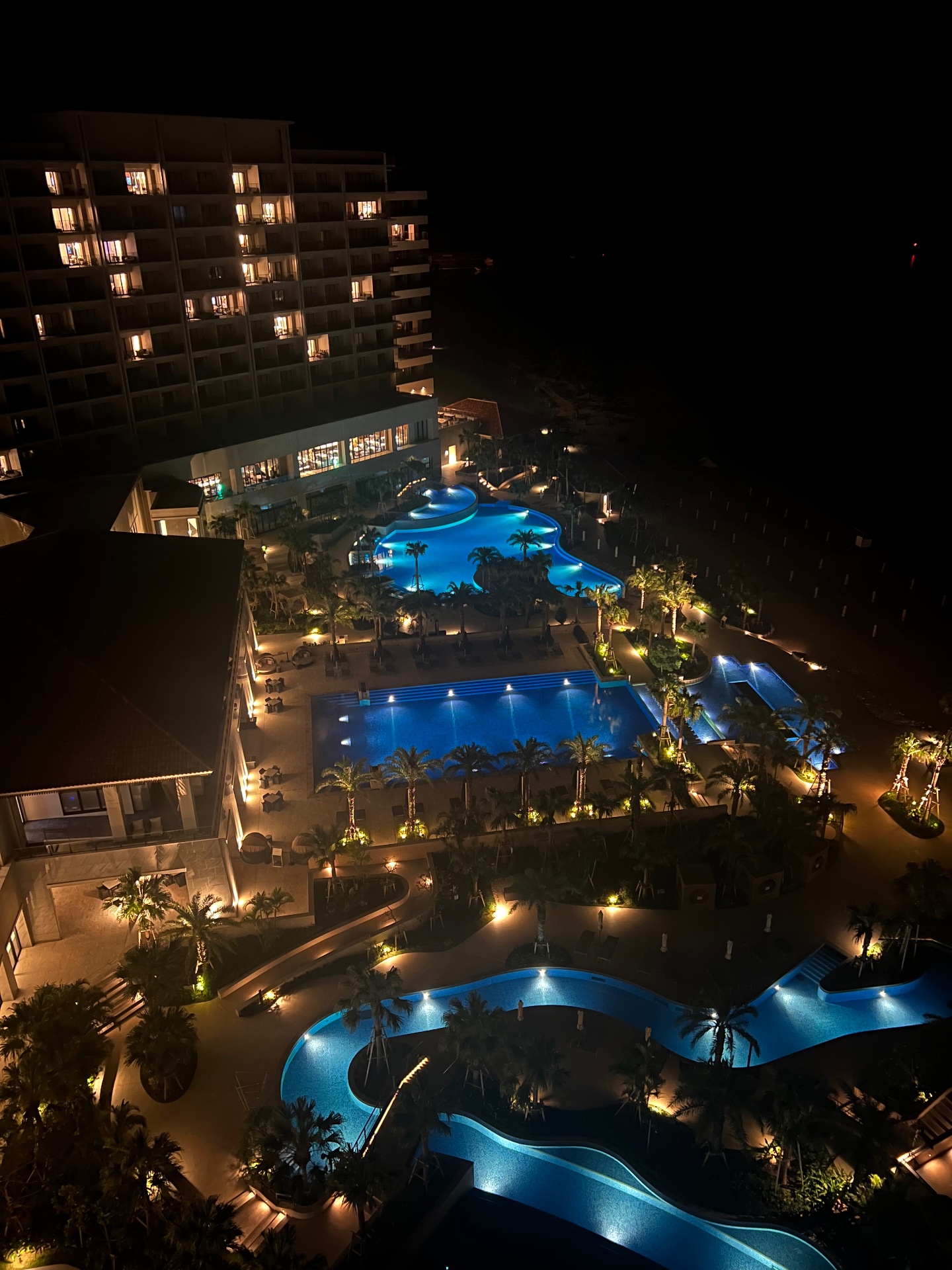Beleuchtete Pools eines Resorts auf Okinawa bei Nacht aus der Vogelperspektive