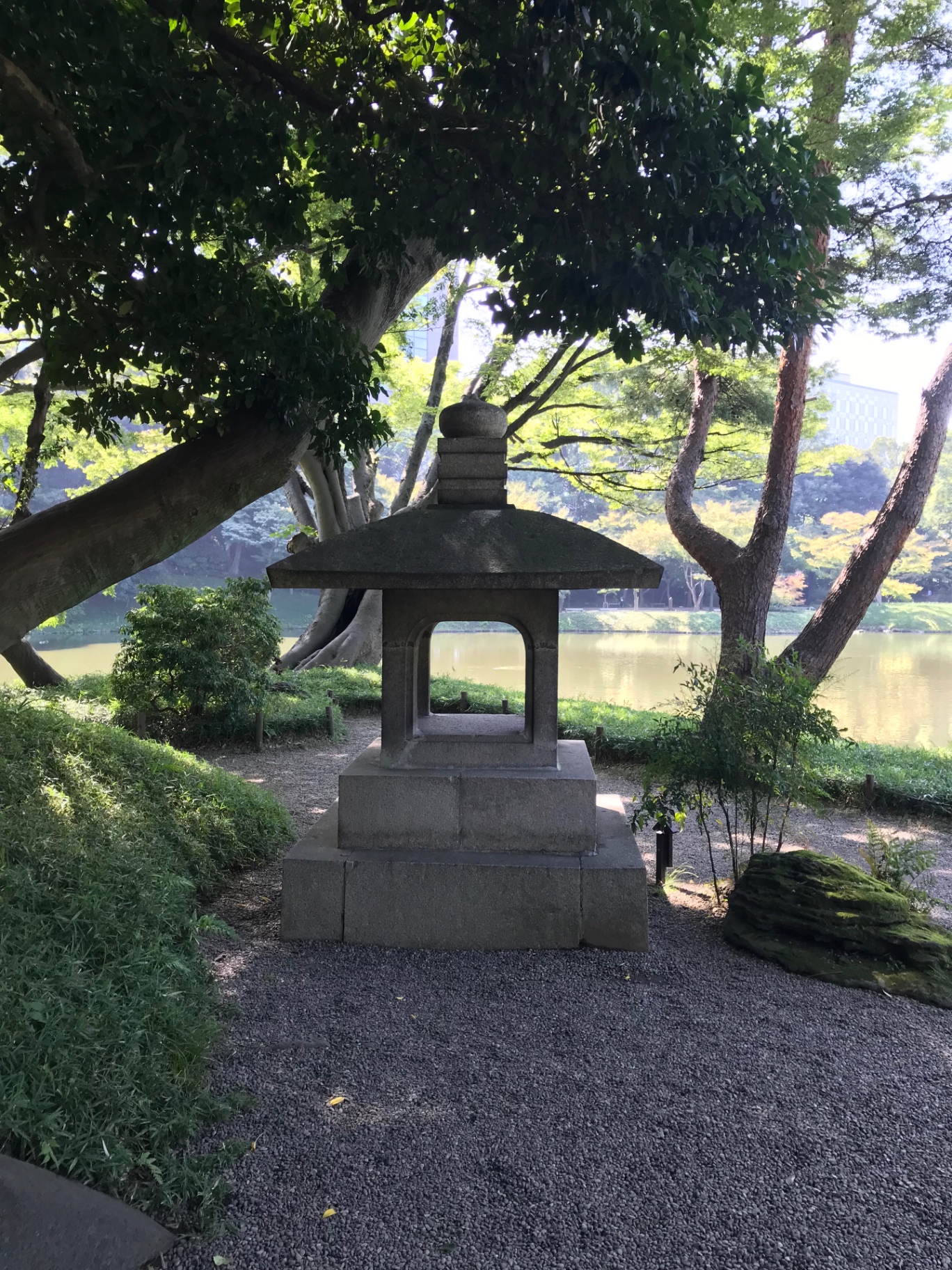Große steinerne Laterne am Teichufer im Koishikawa-Kōrakuen unter alten Bäumen