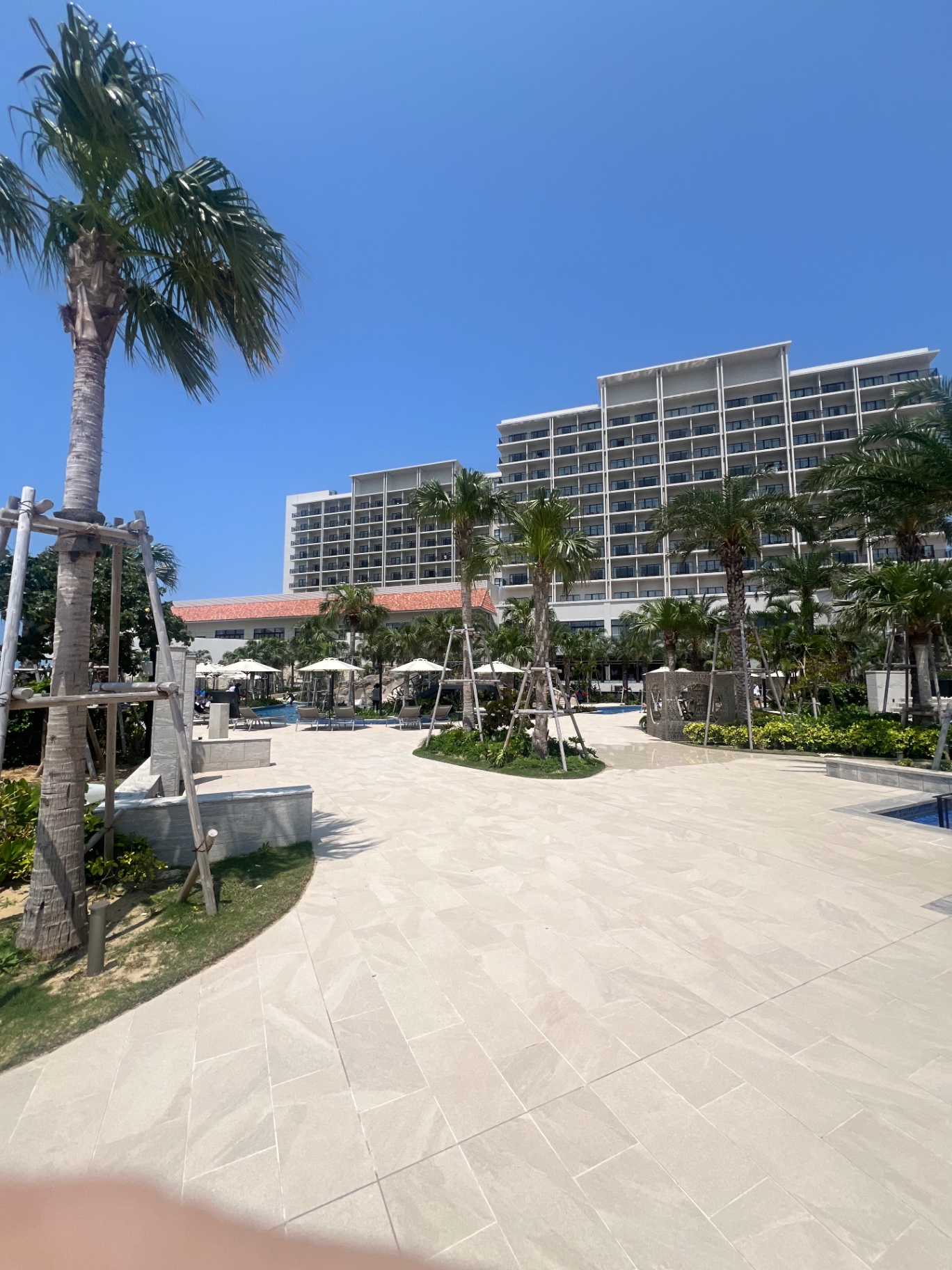 Resortanlage in Okinawa mit Palmen, Sonnenschirmen und strahlend blauem Himmel