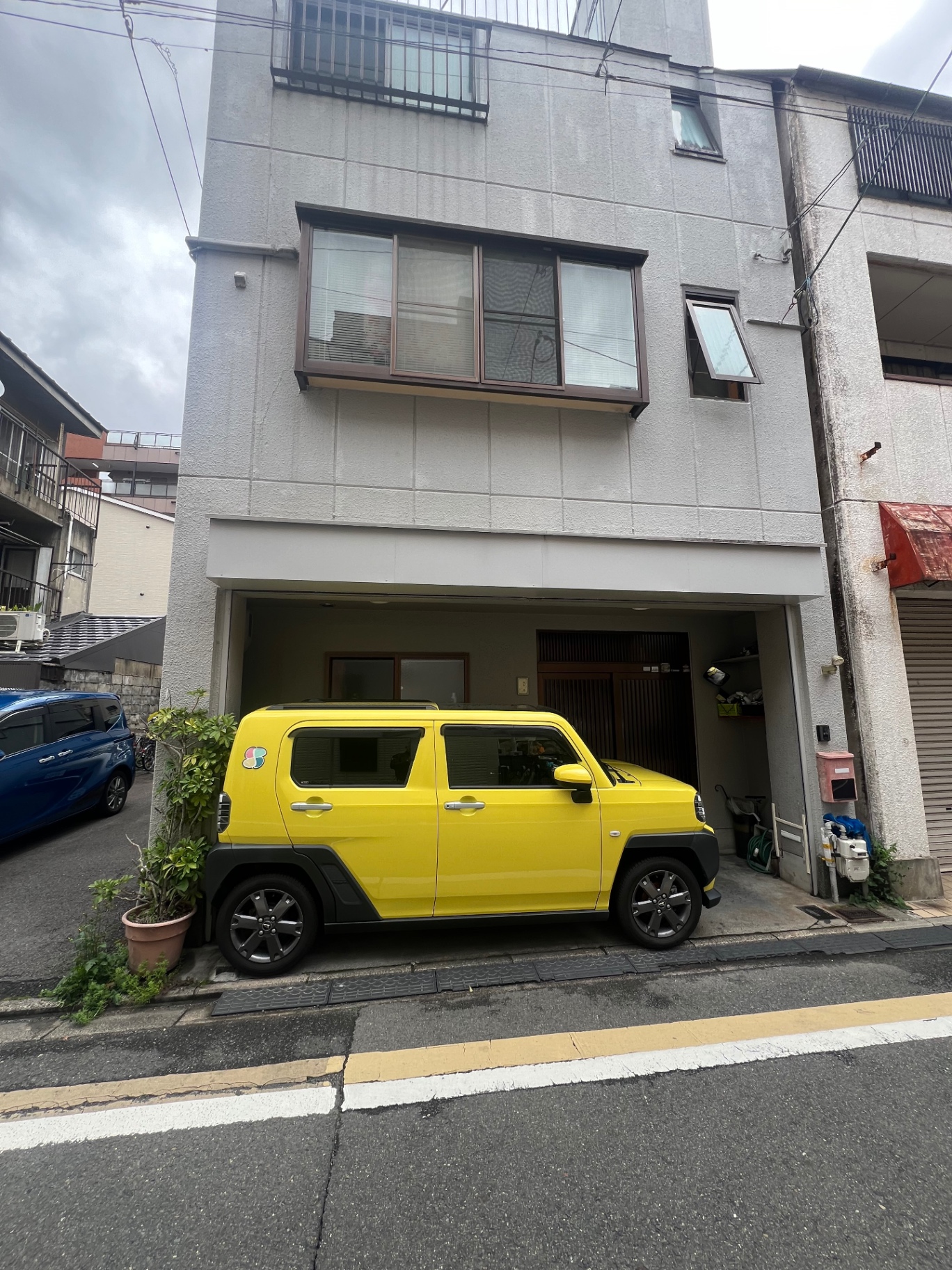 Leuchtend gelber Kei-Car vor einem Wohnhaus in einer Seitenstraße in Kyoto